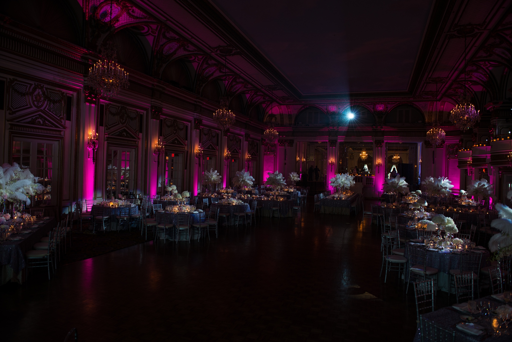Pink uplighting on the columns of a wedding reception ballroom